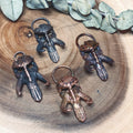 May include: Four metal pendants in the shape of a skull with horns. The pendants are in different shades of copper and bronze.