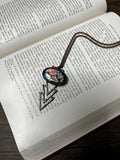 May include: A necklace with a bronze chain and a pendant featuring a triangular design with a blue, green, and purple iridescent glass inlay.