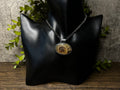 May include: A silver chain necklace with an oval pendant featuring a fossilized ammonite in shades of brown and gold.